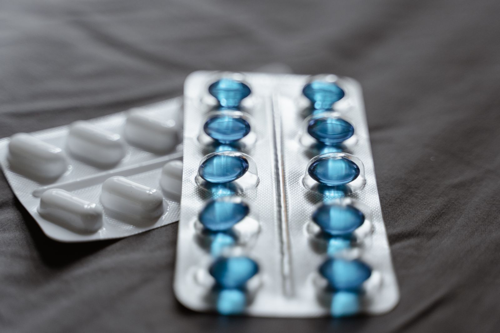 Des gélules bleues et blanches encore scellées dans leurs plaquettes
