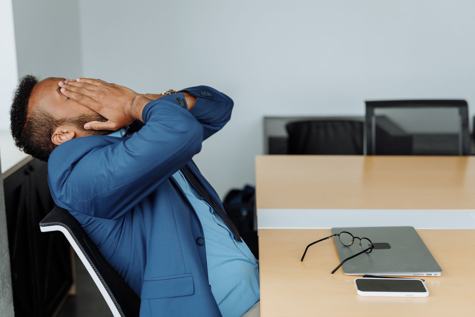 Un salarié se frotte le visage, assis à son bureau en fin de journée