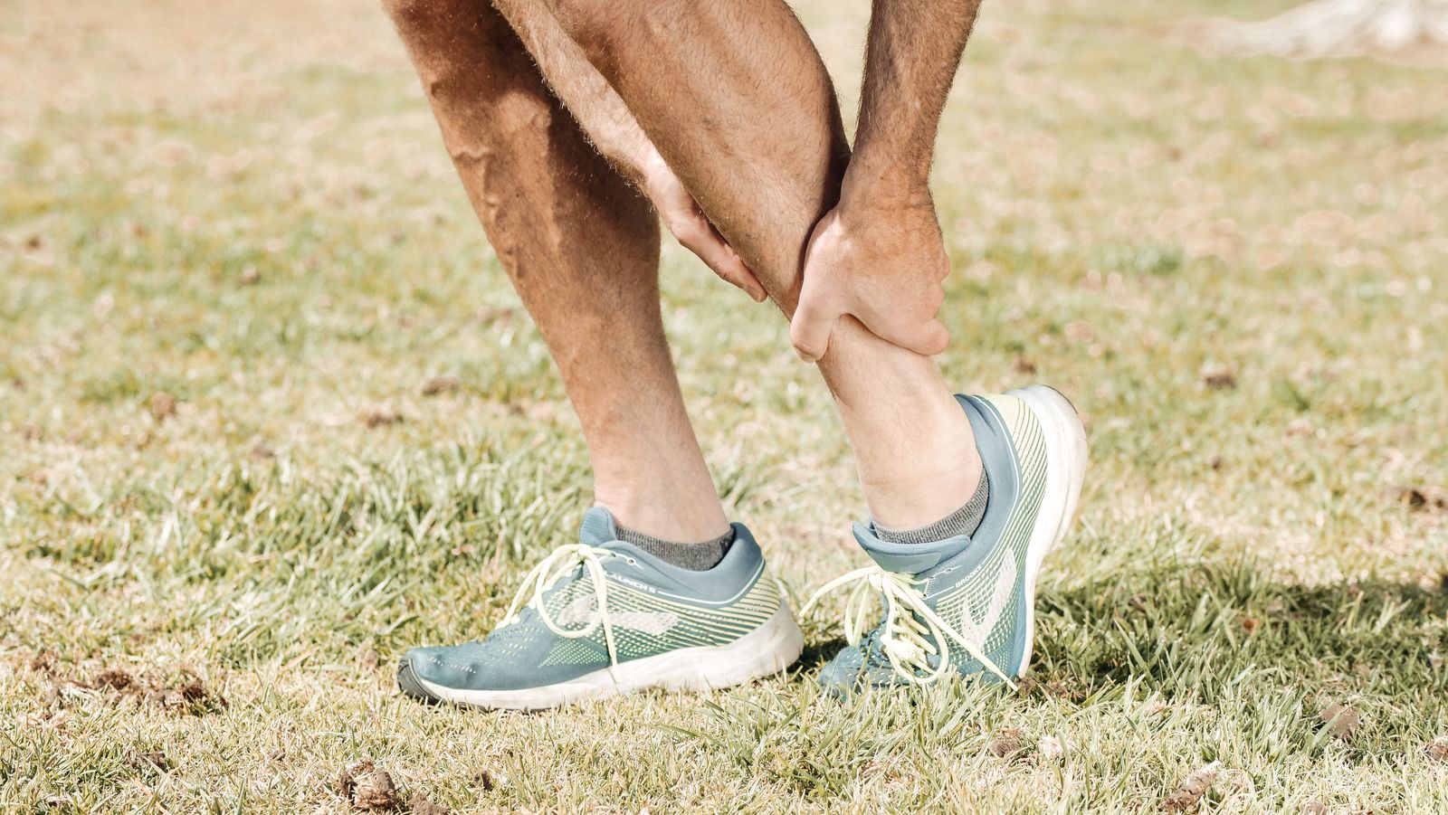 Une personne en chaussures de sport se penche vers le bas de sa jambe