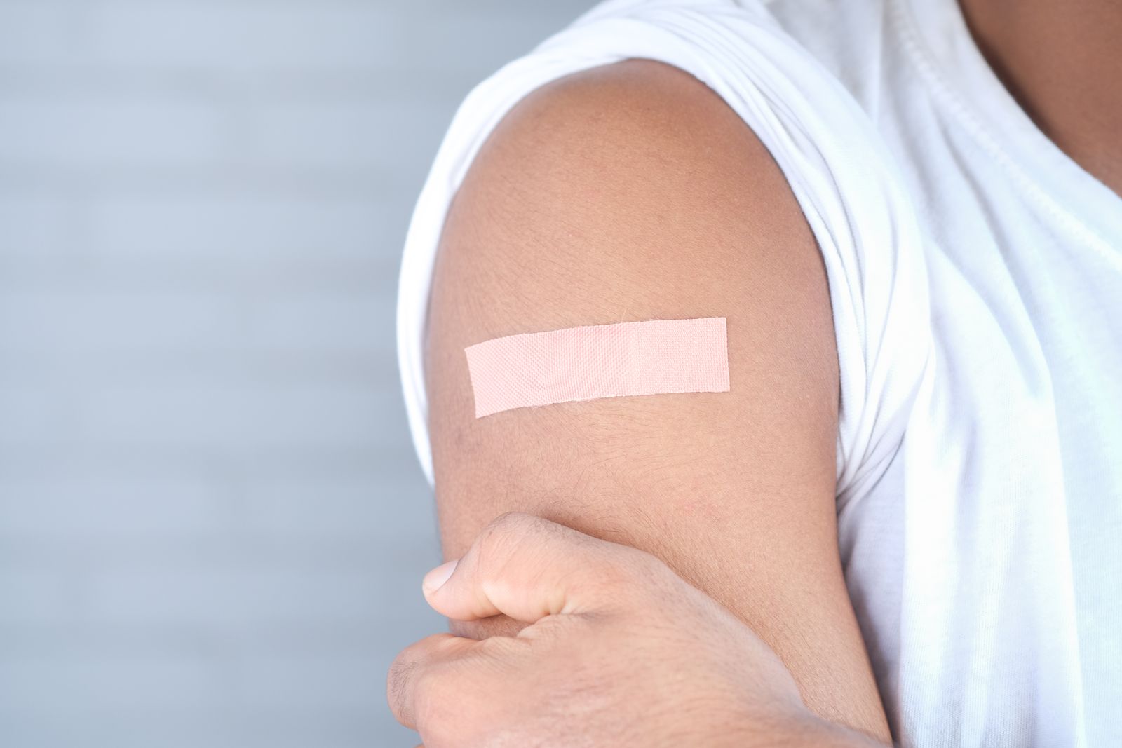 Un pansement beige collé sur le haut du bras après une injection