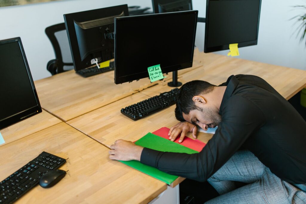 Une personne affalée sur un plan de travail dans un bureau partagé vide